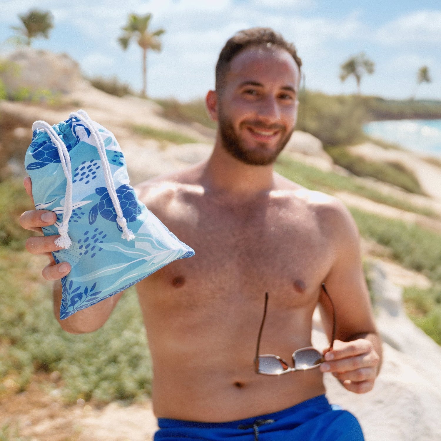A guy holding a Quick Dry, Sand Free, Light Weight, Compact and Ecofriendly Microfiber Beach Towel pouch from La Toalla