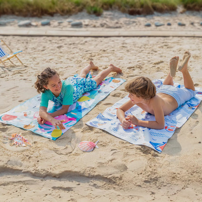 A boy and a girl each sitting on a kids Quick Dry, Sand Free, Light Weight, Compact and Ecofriendly Microfiber Beach Towel from La Toalla