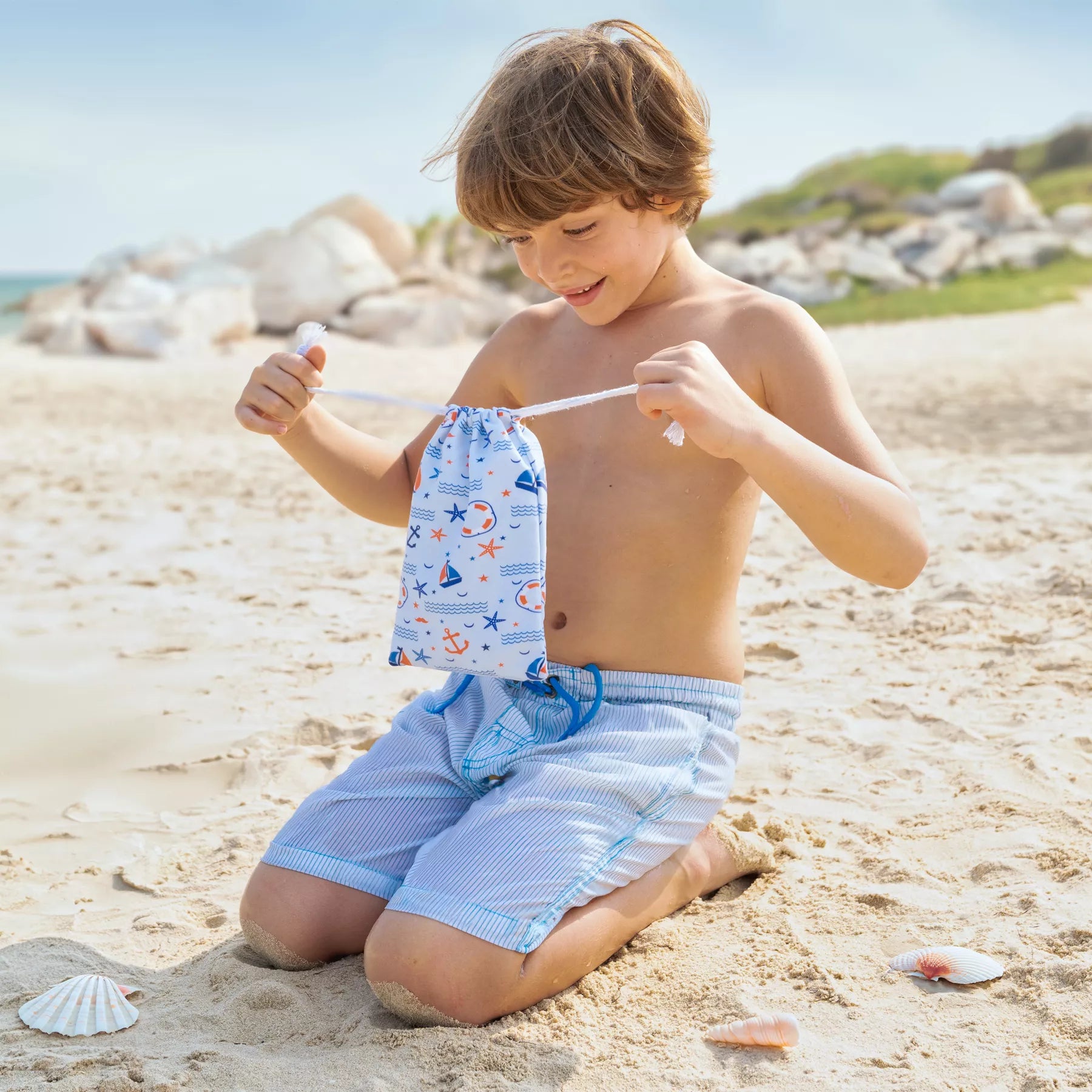 A boy holding a Quick Dry, Sand Free, Light Weight, Compact and Ecofriendly Microfiber Beach Towel pouch from La Toalla