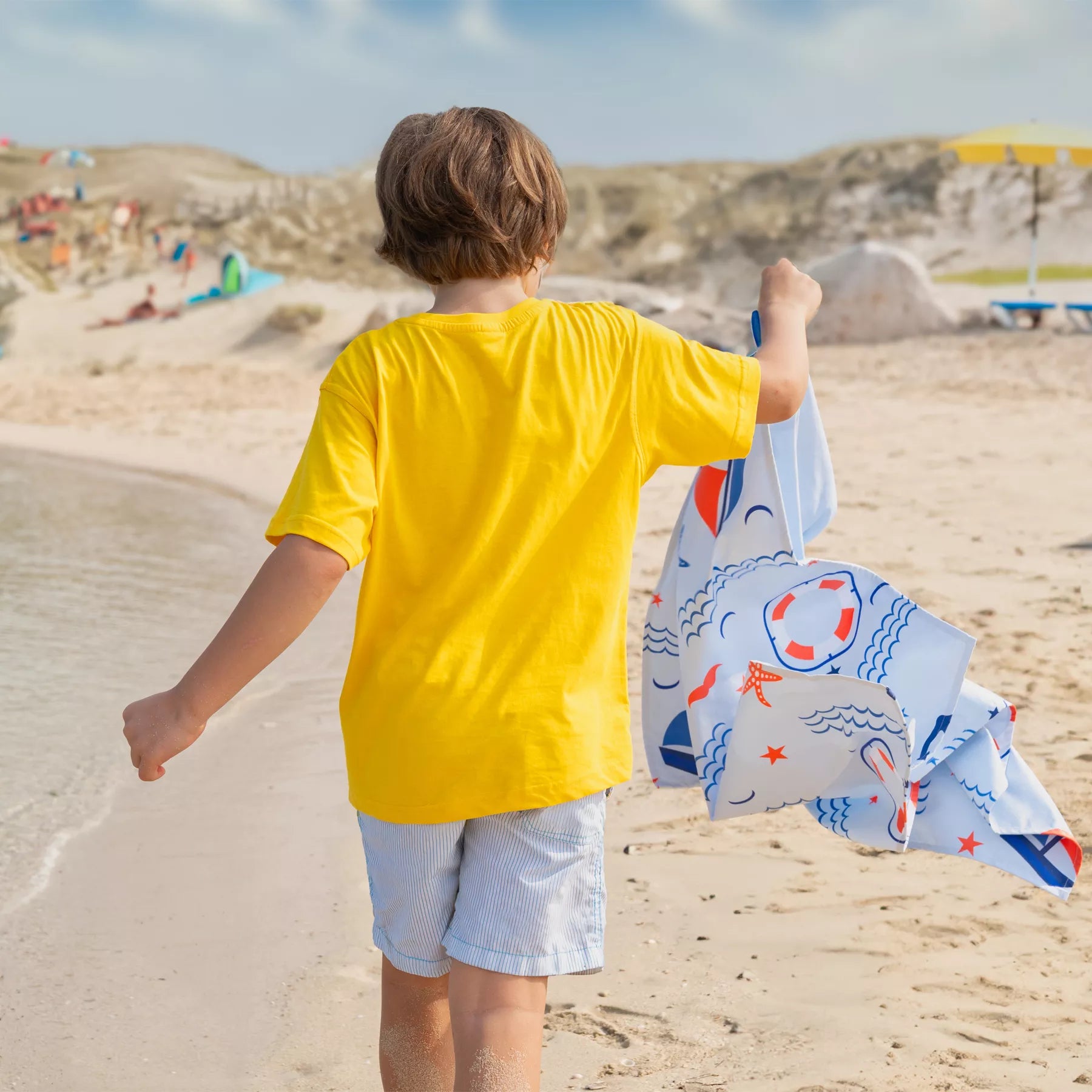 A boy holding a Quick Dry, Sand Free, Light Weight, Compact and Ecofriendly Microfiber Beach Towel from La Toalla designed for kids