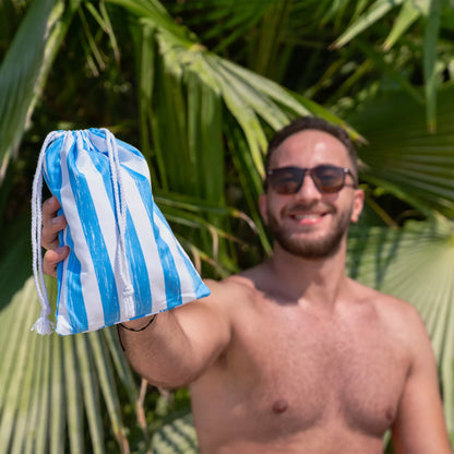 A guy holding a Quick Dry, Sand Free, Light Weight, Compact and Ecofriendly Microfiber Beach Towel Pouch from La Toalla