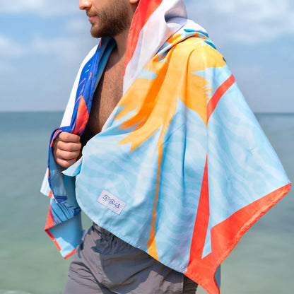 A guy wrapped in a Quick Dry, Sand Free, Light Weight, Compact and Ecofriendly Microfiber Beach Towel from La Toalla