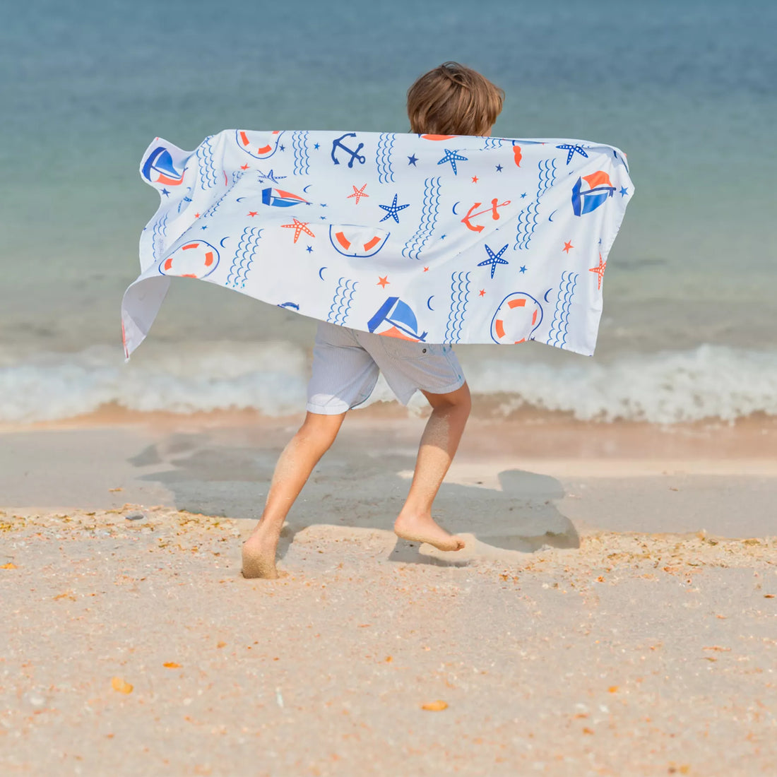 A kid holding a Quick Dry, Sand Free, Light Weight, Compact and Ecofriendly Microfiber Beach Towel from La Toalla designed for kids
