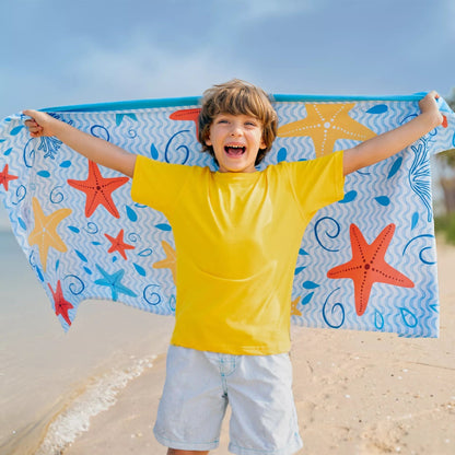 A happy kid holding a Quick Dry, Sand Free, Light Weight, Compact and Ecofriendly Microfiber Beach Towel from La Toalla designd for kids